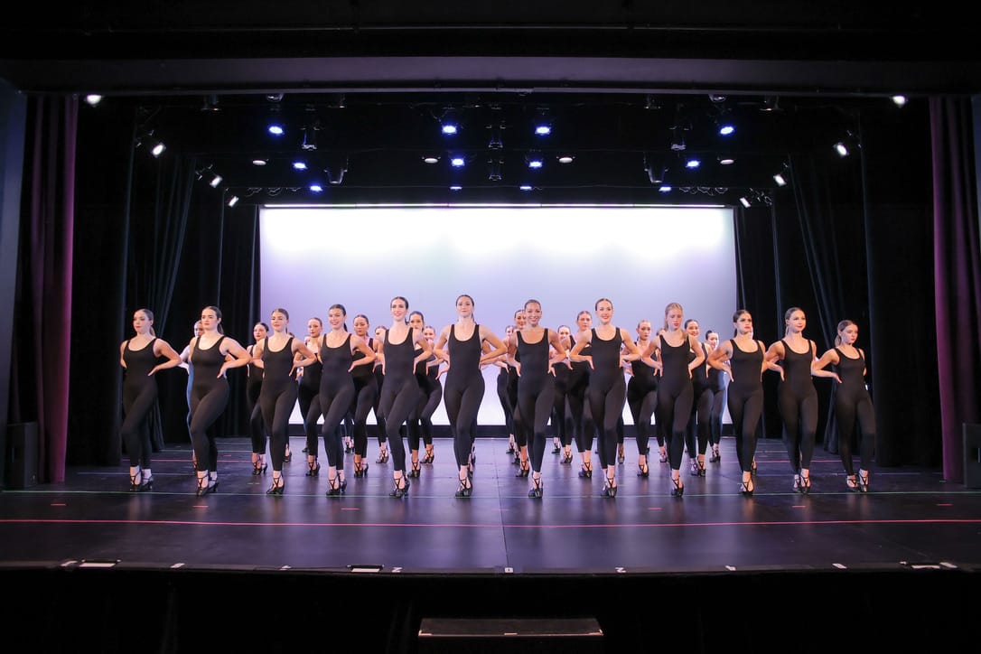 Full company in synchronized formation on stage