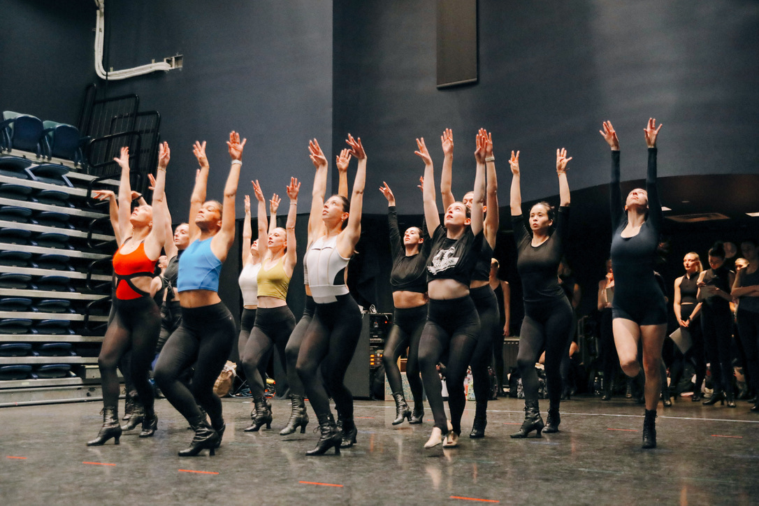 Dancers reaching upward in synchronized rehearsal movement