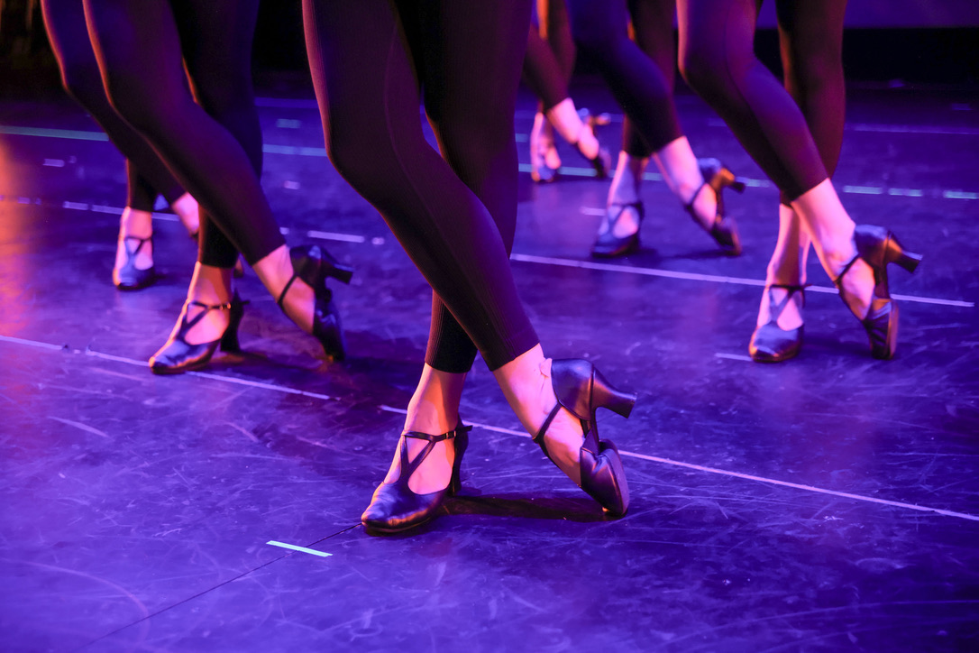 Dancers feet in precision formation under stage lights