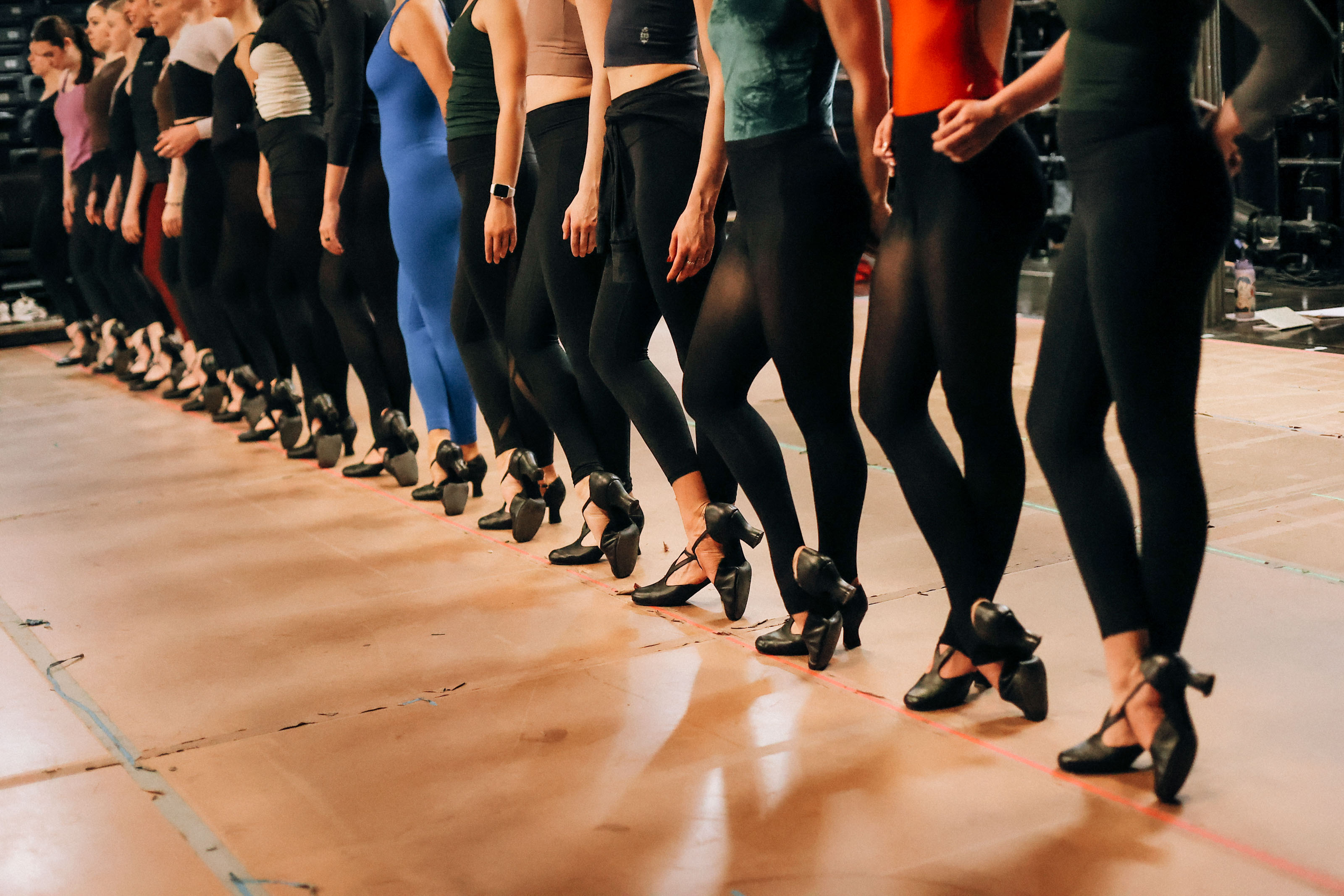 Precision kickline formation showing dancers in synchronized line during rehearsal
